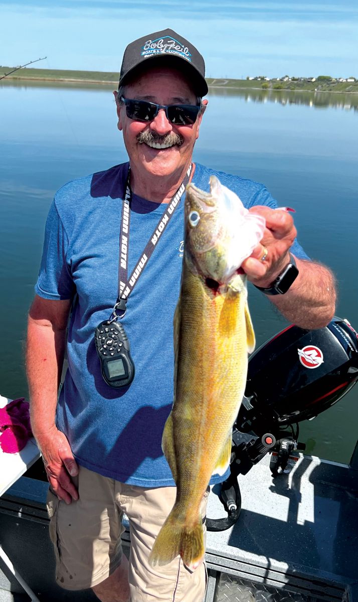 Dave holding a large walleye caught on Moses Lake, with the scenic backdrop of the lake.