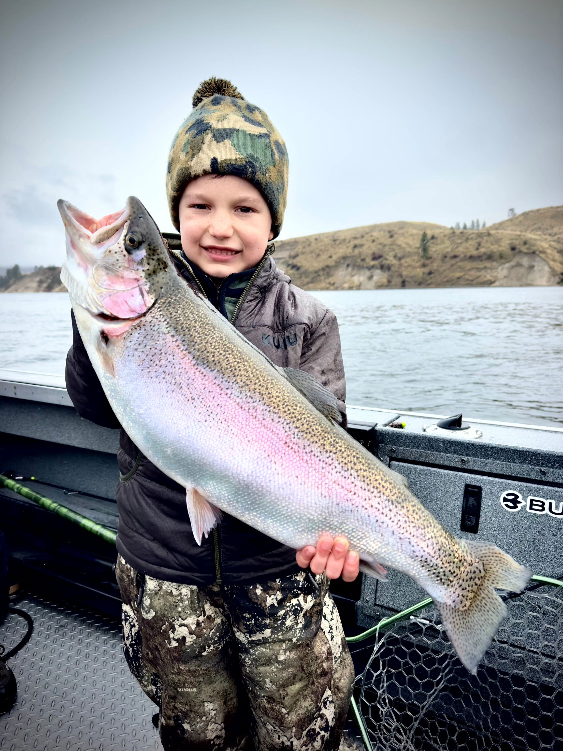 A youngster proudly holding a 12-pound triploid trout caught at Rufus Woods Reservoir, showcasing winter fishing potential.