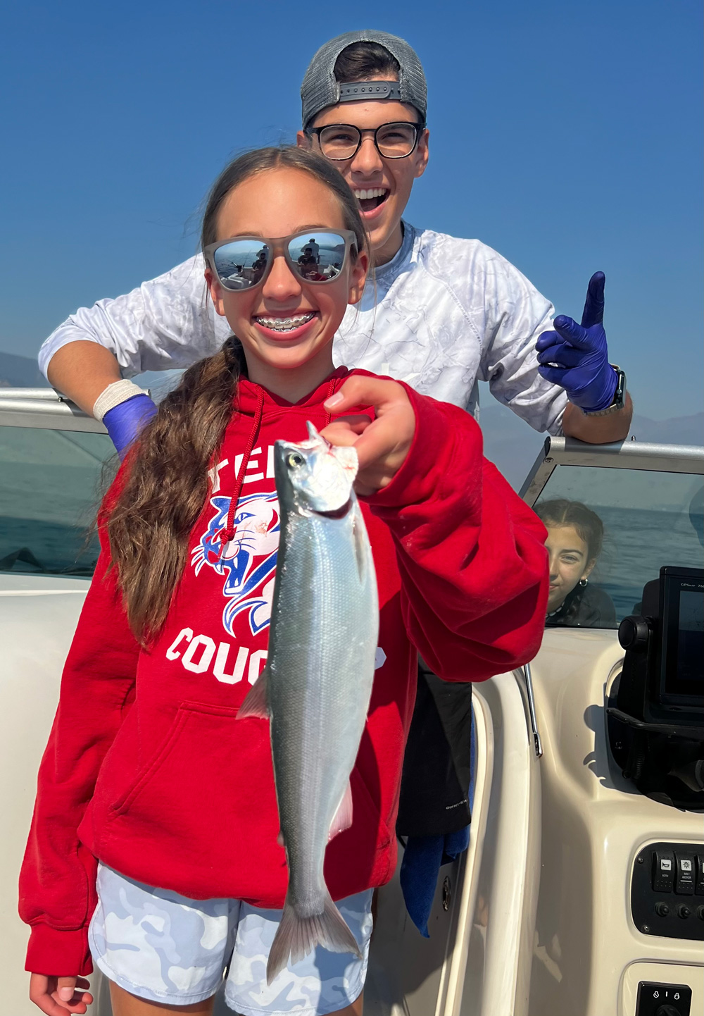 Brinley holding a kokanee fish caught on Lake Chelan, with her brother Josh in the background.