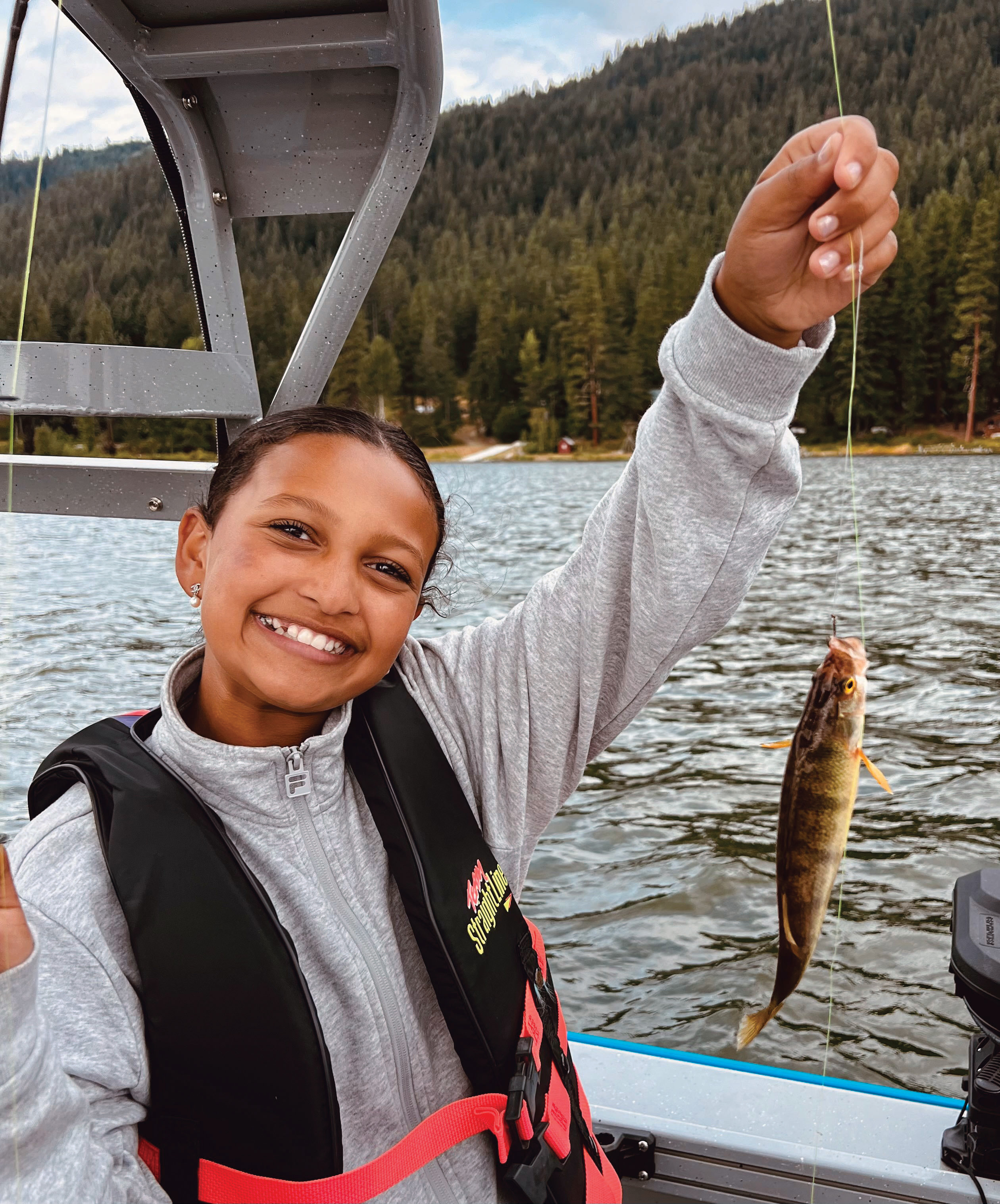 Mabel Jima holding a perch she caught at Fish Lake, showcasing her successful fishing trip.