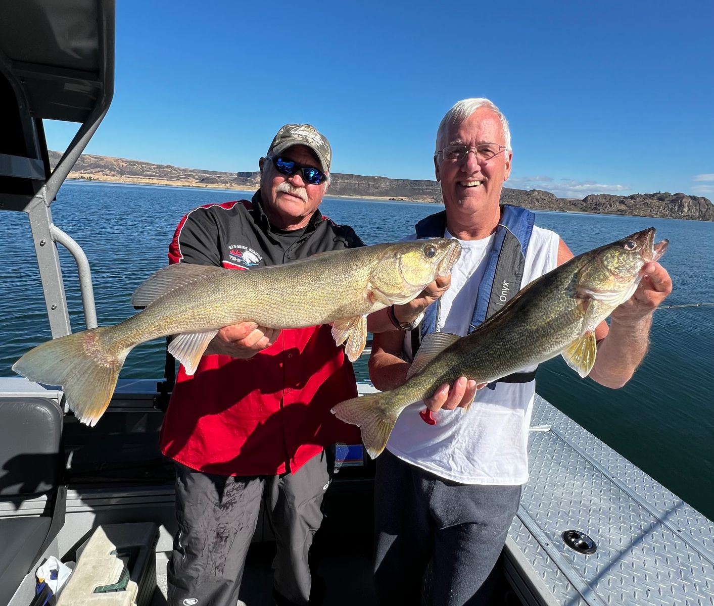 Brian Neilson and Mike Wren holding two large walleye caught on Banks Lake, showcasing the success of their fishing trip.